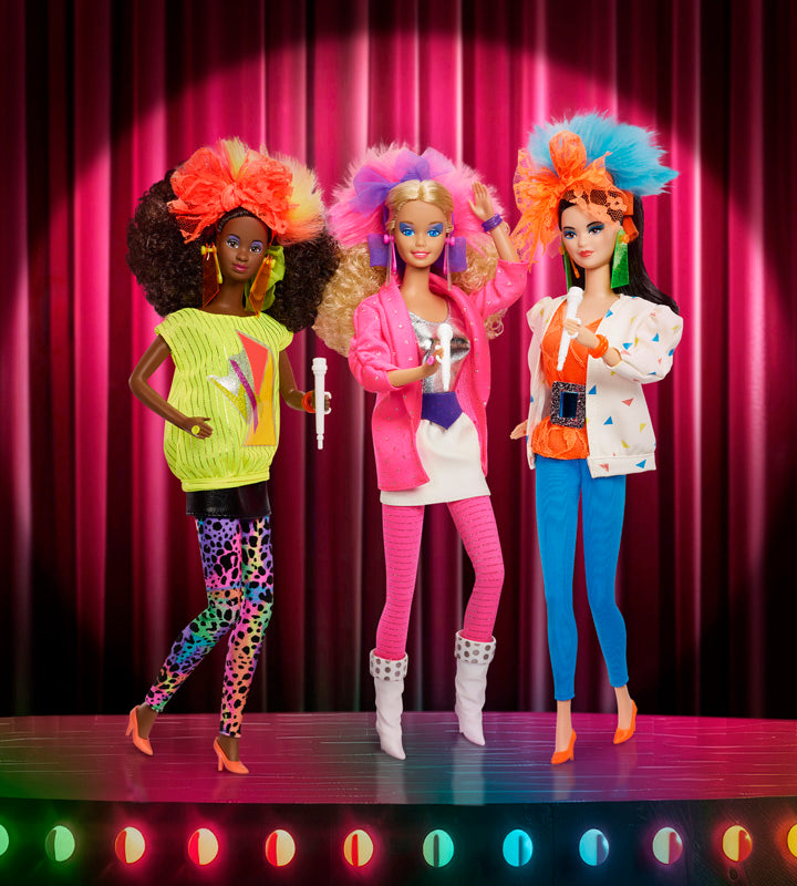 Three Barbie and the Rockers 40th anniversary reproduction dolls with colorful hairstyles and outfits against a pink curtain background
